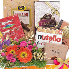 Flower delivery hamper with vibrant gerbera daisies, pink roses, and assorted chocolates.