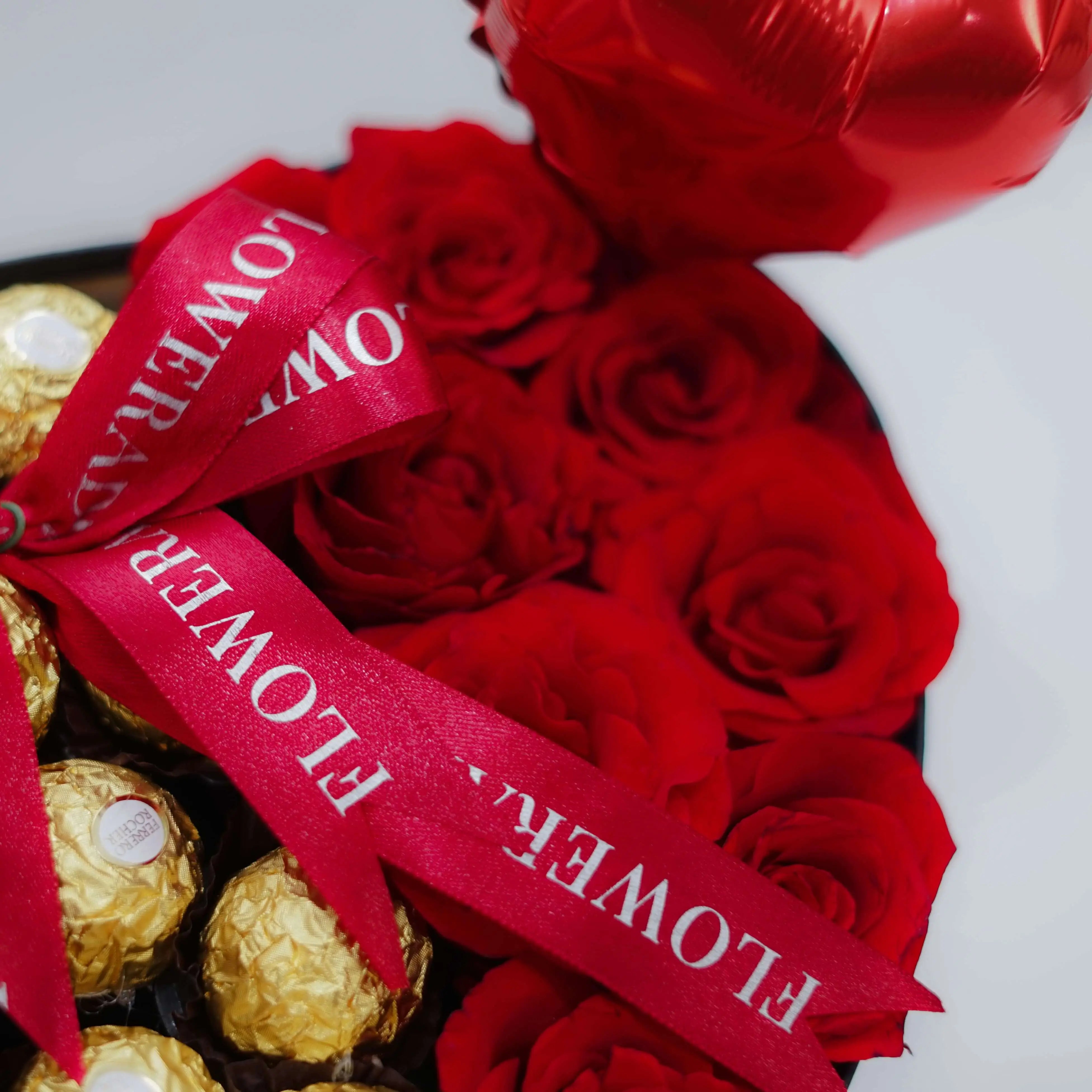 Red rose flower arrangement with gold chocolates and ribbon, ideal for flower delivery gift.