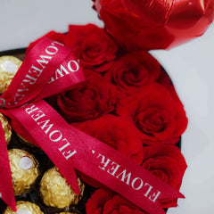 Red rose flower arrangement with gold chocolates and ribbon, ideal for flower delivery gift.