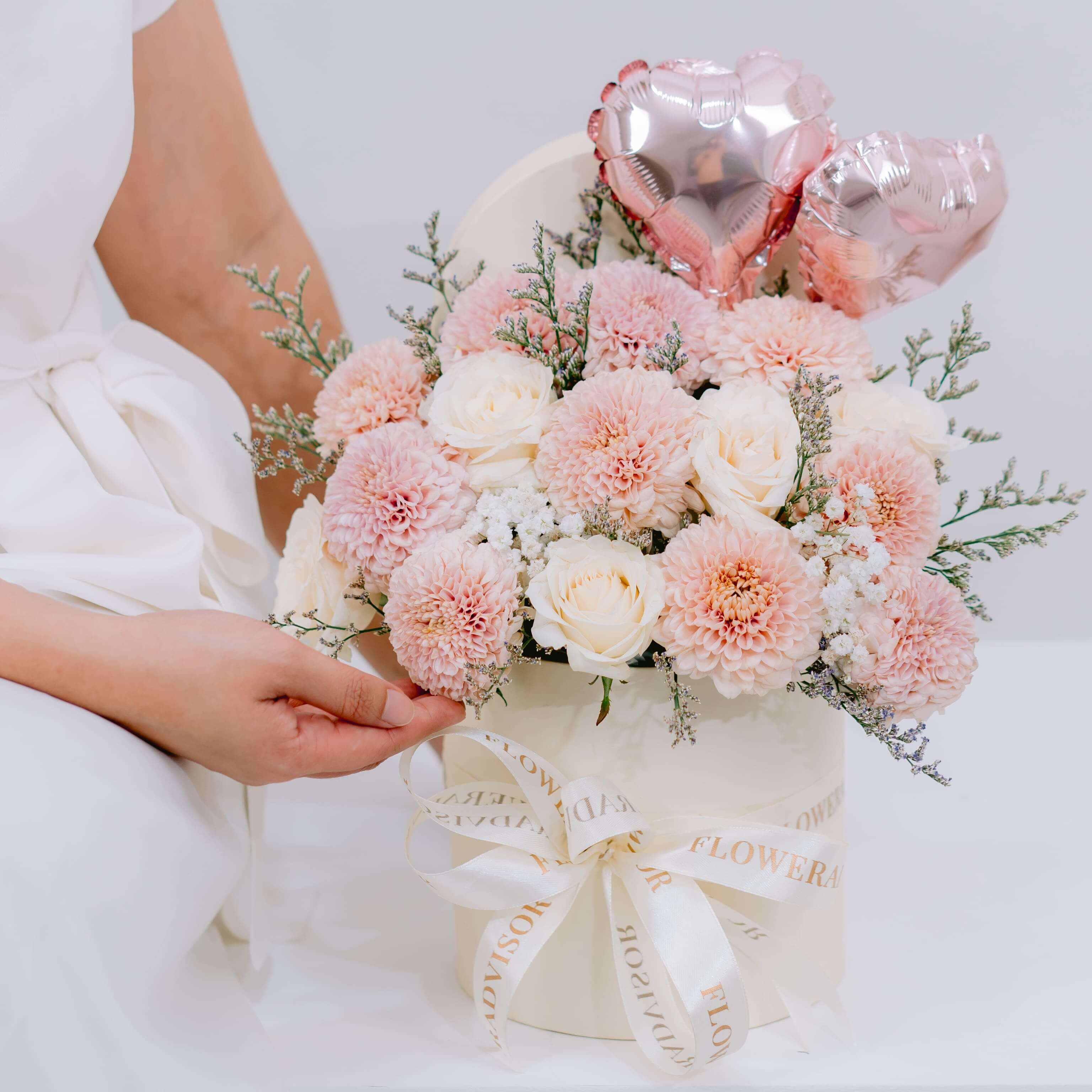 Elegant pink and white flower arrangement in hat box with heart balloons for delivery