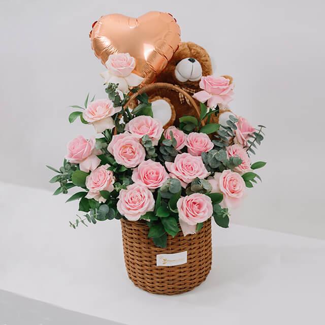 Flower delivery basket with pink roses, teddy bear, and heart balloon