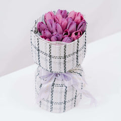 Elegant bouquet of fresh purple tulips in a checked fabric wrapper for flower delivery