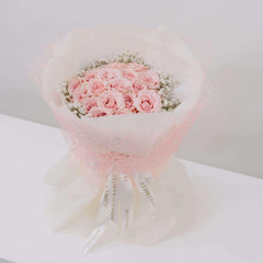 Elegant flower delivery bouquet with pink roses and baby’s breath, wrapped in pastel paper.