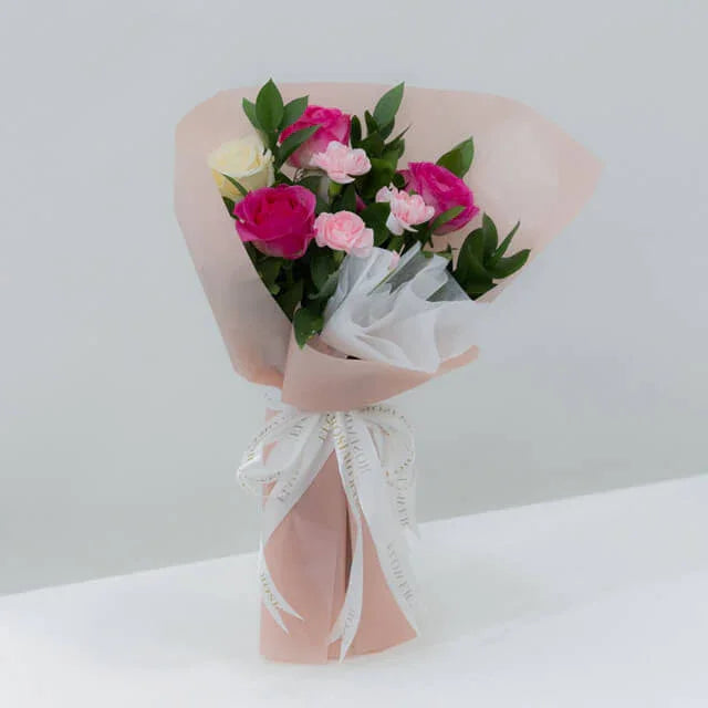 Bouquet of pink and white roses with greenery in pastel wrapping, flower delivery option
