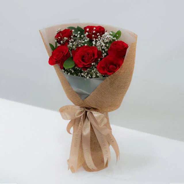 Red rose bouquet with baby’s breath, wrapped in brown paper for flower delivery