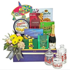 Flower delivery gift hamper with fresh yellow flowers, gourmet snacks, cookies, and tea set
