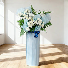 White flower arrangement with ferns and blue wrapping, perfect for Singapore flower delivery